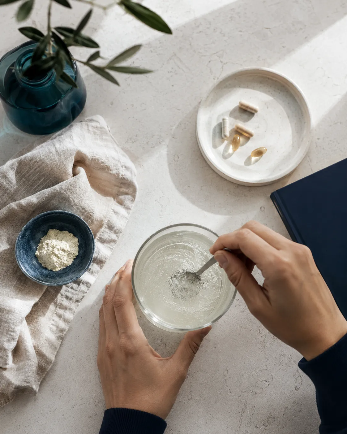 Overhead of a daily supplement ritual, stirring powder into water