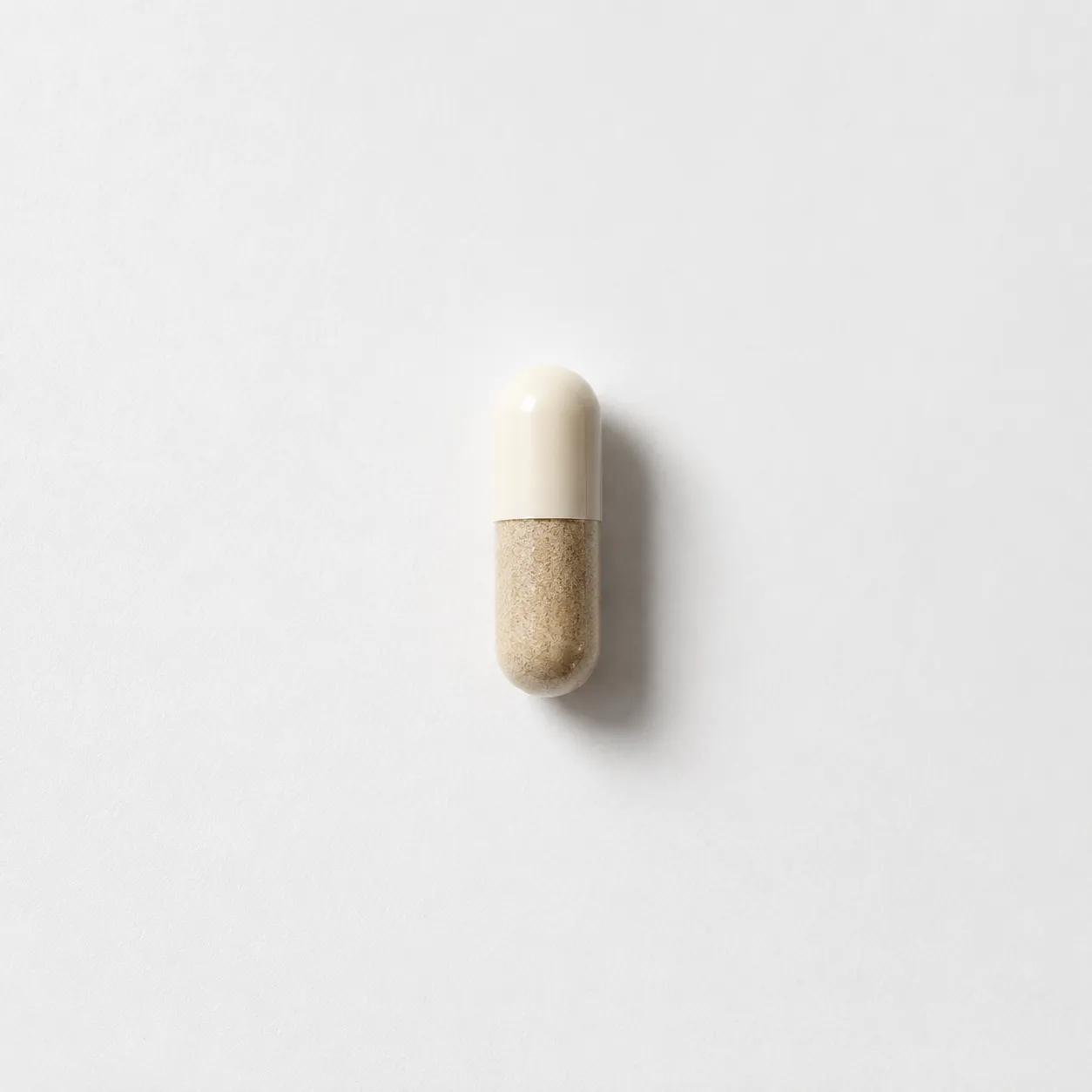 A single two-tone supplement capsule, one half filled with a natural powder blend